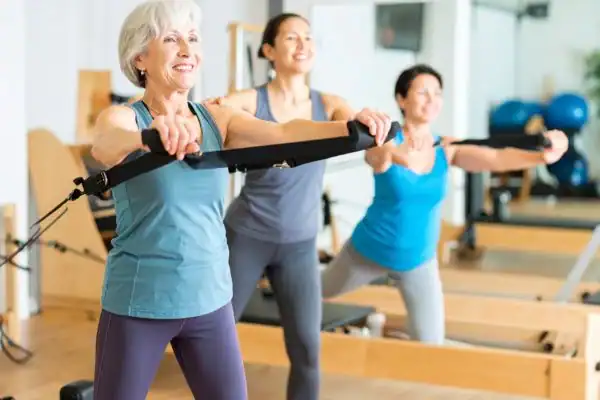 Toning Arms After 60: Empowering Womens Fitness Through Effective Weight Training 2 older woman doing weight training Beccles and resistance in the gym to tone upper arms