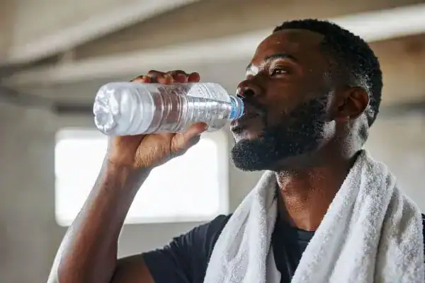 Image of man drinking water to improve hydration Beccles after work out.